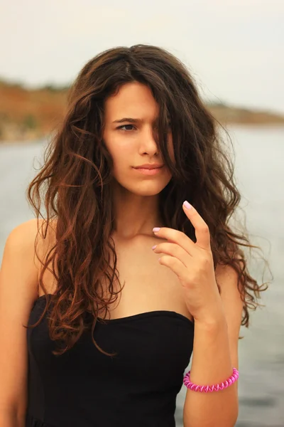 Beautiful slim brunette girl model posing in fashion dress by the sea