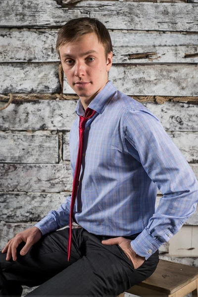 A young man in a light shirt and red tie, office employee posing in studio