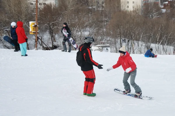 Young snowboarder and instructor during the descent from the mountain ski resort