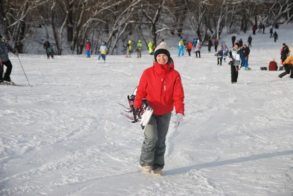 The young girl in a red jacket snowboarder goes down the slope at a ski resort in Moscow