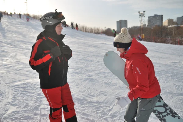 Young snowboarder and instructor during the descent from the mountain ski resort in Moscow
