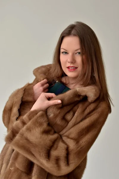 Young girl with long hair in a long coat of fur