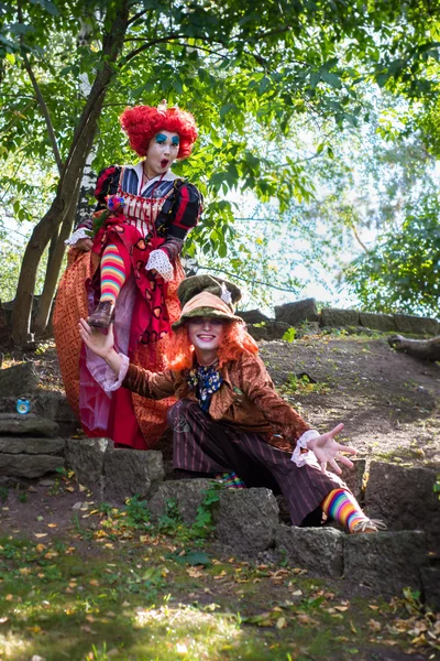 Young woman and man in the image of the Hatter and the Red Queen from the fairy tale about Alice