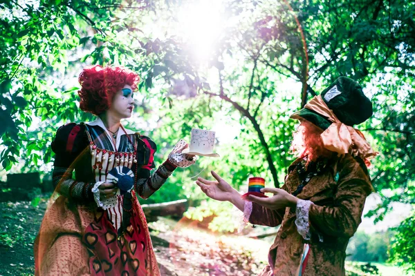 Young woman and man in the image of the Hatter and the Red Queen from the fairy tale about Alice