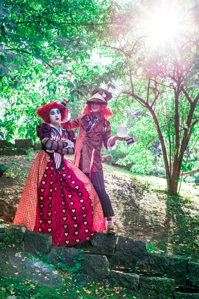 Young woman and man in the image of the Hatter and the Red Queen from the fairy tale about Alice