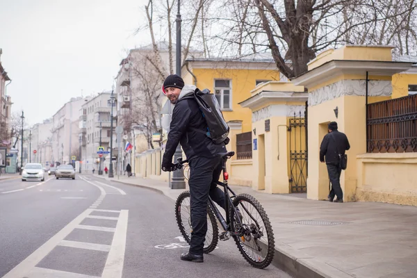 A young man riding a bicycle through the city in autumn day