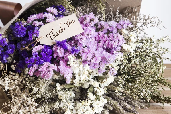 Bouquet of dried flowers with thank you card on the wooden table