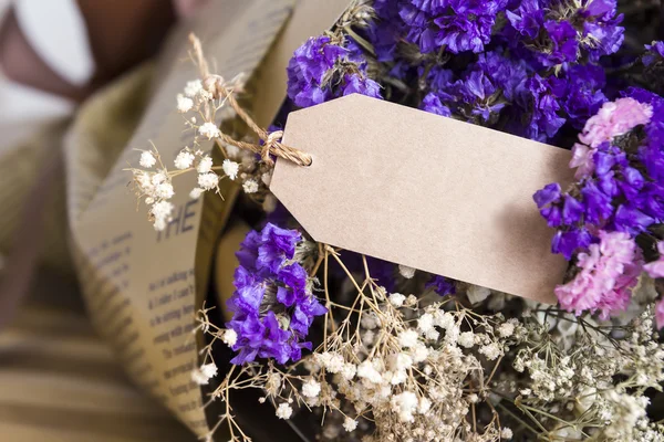 Bouquet of dried flowers with blank paper tag on the wooden tabl