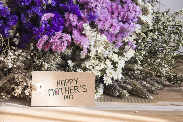 Bouquet of dried flowers with mothers day card on the wooden tab