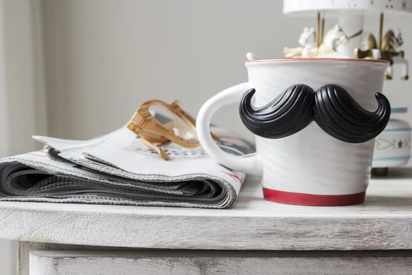 Cup with mustache on vintage cabinet for fathers day concept