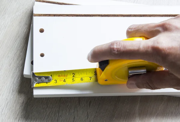 Man measuring home furniture with measure tape