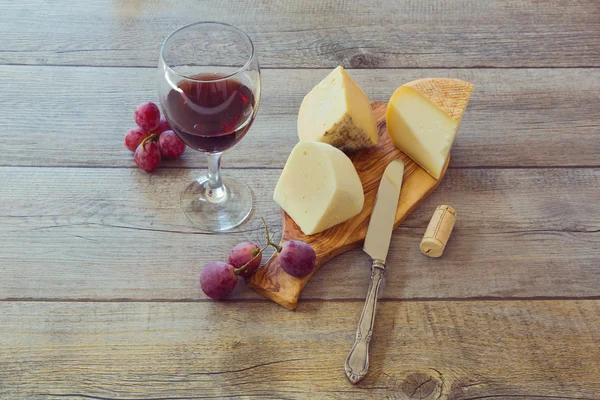 Wine, cheese and grapes on wooden table