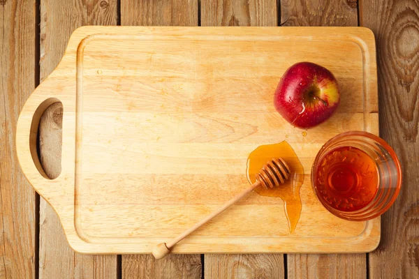 Apples and honey on wooden board