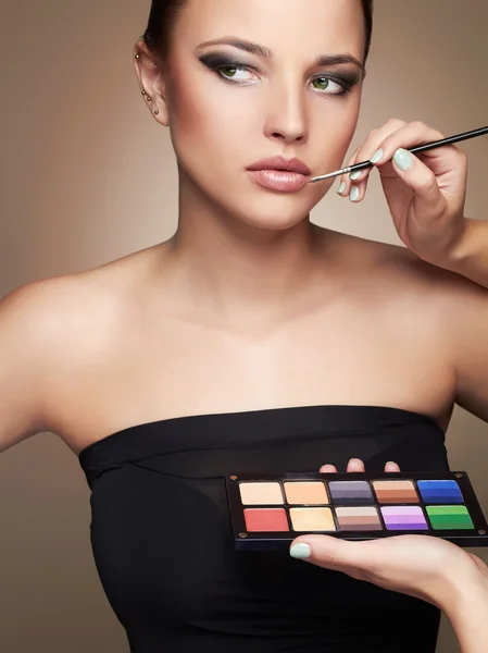 Beautiful woman face. beauty girl with Perfect make-up.Makeup artist applies lipstick