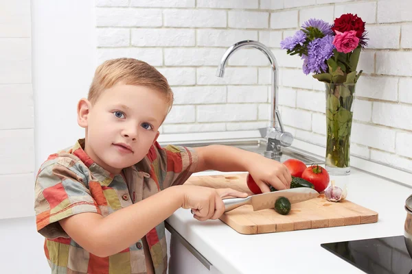 Funny child boy. Healthy food at home.handsome little boy cooking in the kitchen.little chef cuts vegetables