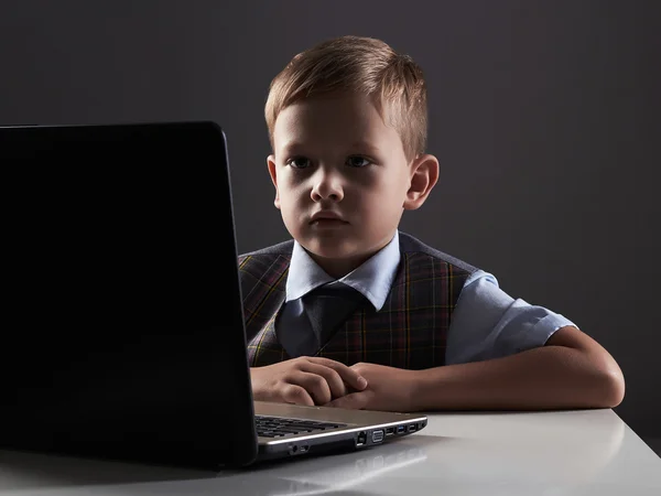 Young boy looking in the notebook screen. funny child with computer