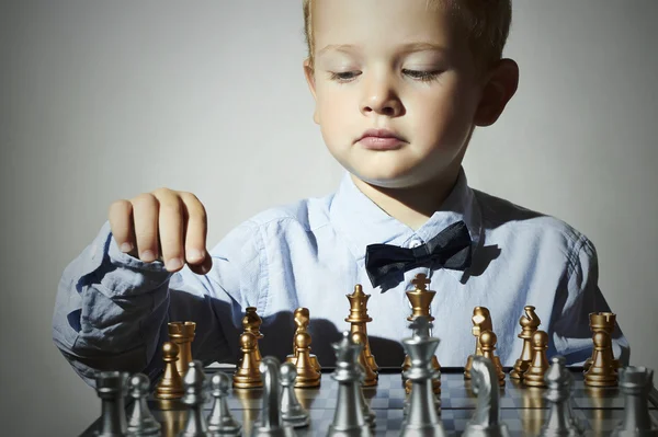 Little boy playing chess.Smart kid.fashion children.5 Years Old Child.Little genius Child. Intelligent game.Chessboard