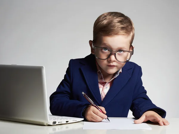 Young businessman using a laptop. Funny child in glasses