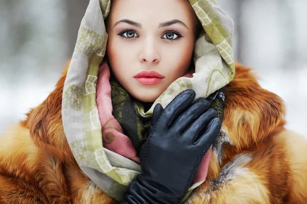 Beauty model in winter forest. beautiful young Woman in fashionable Fur Coat,leather gloves and scarf.