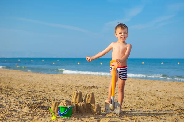 Kid plays with sand at the seashore in summertime