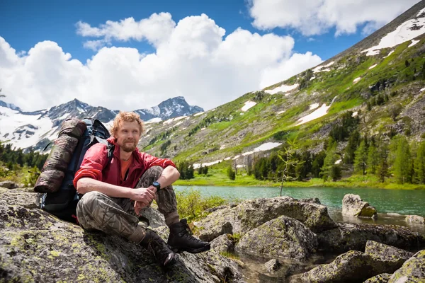 Hiker is posing at camera in mountains of Altai