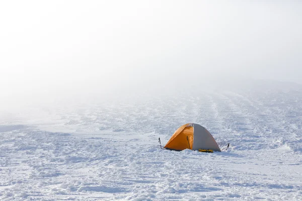 Orange tent in winter mountains on sunny day