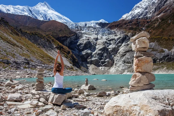 Young woman is practicing yoga at mountain lake