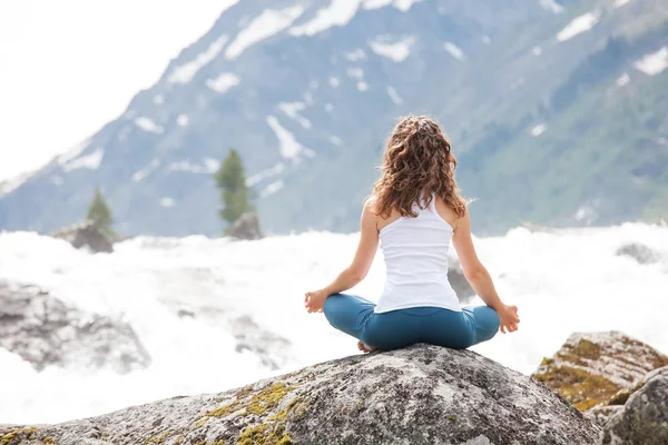 Young woman is practicing yoga at mountain river