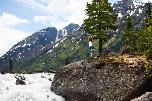 Young woman is practicing yoga at mountain river