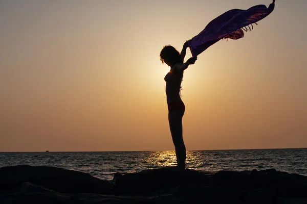 Silhouette of woman that stands against sunset sun at the seasho