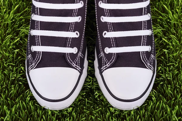 Pair of black and white sneakers on green meadow