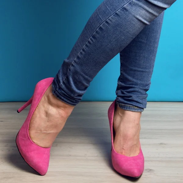Woman legs in blue jeans and pink high heel shoes