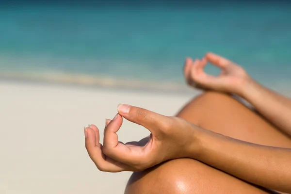 Woman sitting on the beach in lotus pose