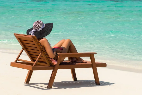 Young woman sunbathing on lounger at tropical beach