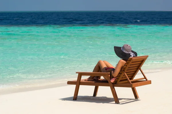 Young woman sunbathing on lounger at tropical beach