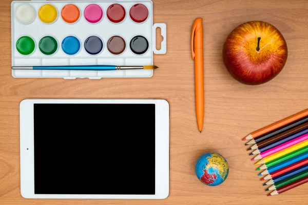 School supplies and tablet on wooden school desk from above