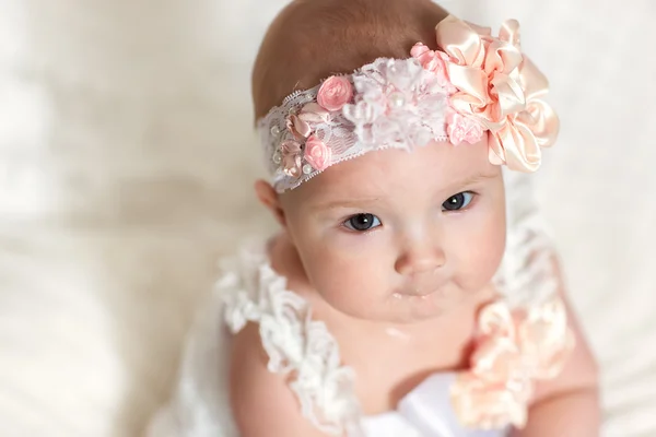 The girl in the headband with flowers looking at the camera from the bottom up