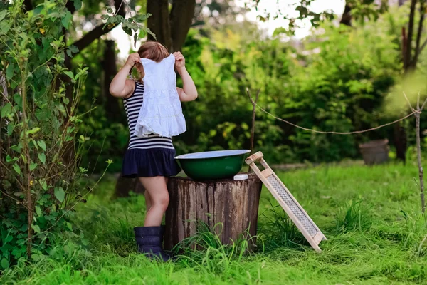 Little helper girl washes clothes in a basin outdoors