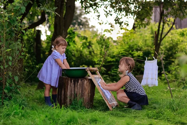 Little helper girls sisters washes clothes using the washboard o