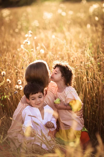 Mother hugging her son and daughter in a wheat field