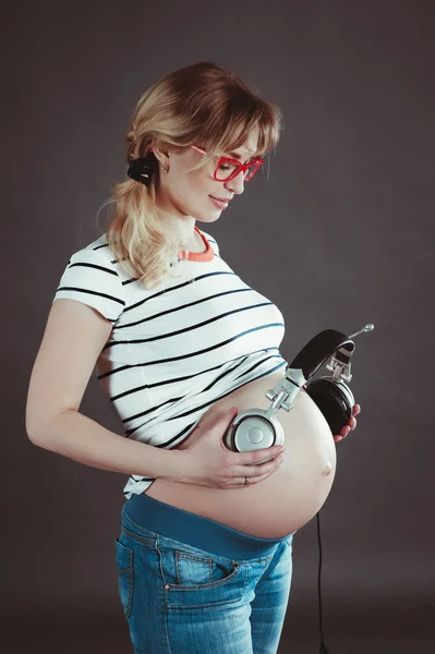 Belly of a pregnant woman. Listen to music with headphones.