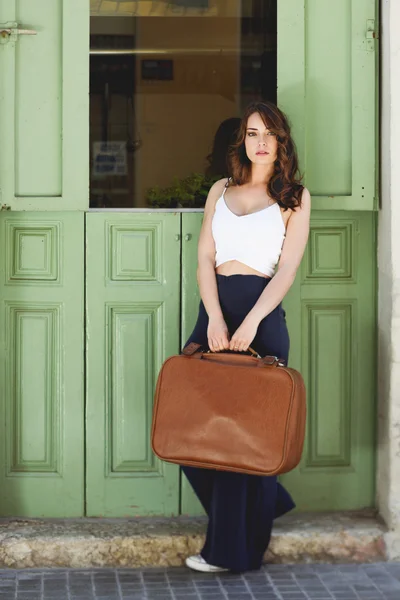 Beautiful girl with vintage bag against green door
