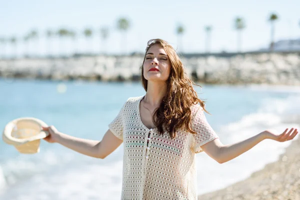 Woman with open arms deep breathing in the beach.