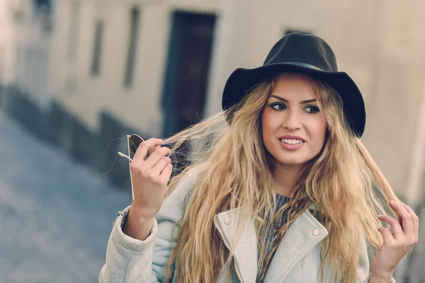 Woman looking with her curly blonde hair in urban background