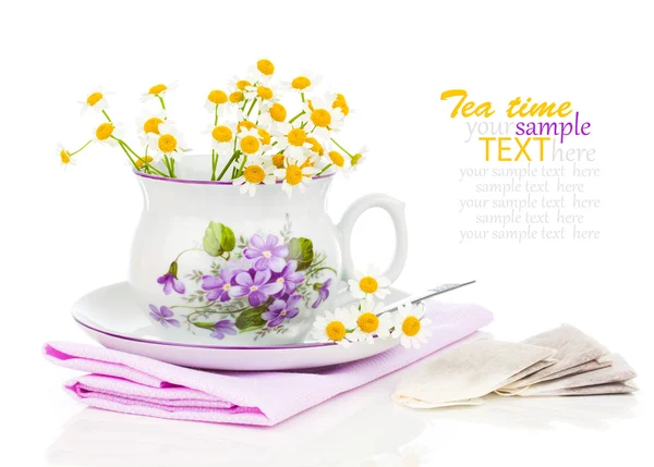 Cup with fresh camomile flower and tea bags, isolated on white