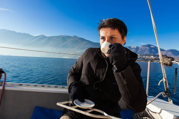 Woman makes a coffee break on the sail boat