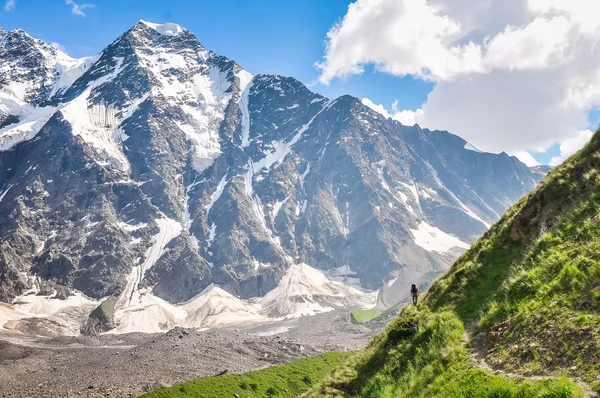 Tourist walking on a steep slope on a background of mountain