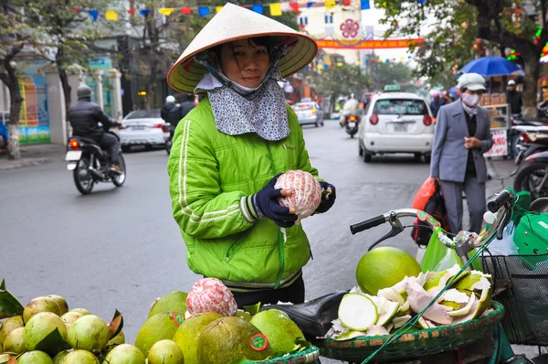Saleswoman in a straw hat sells fruit