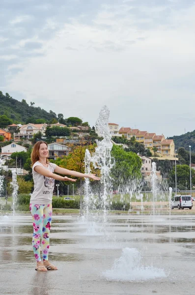 Splashing water of fountain. Girl enjoying Fountain jets