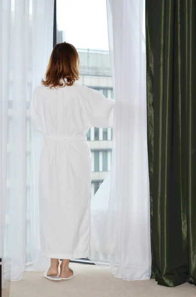Back Portrait of woman in a white bathrobe near the window